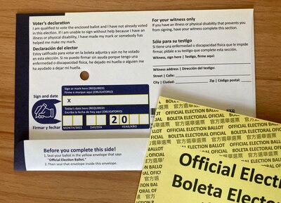 A white and blue mail in voting ballot on a wood table.